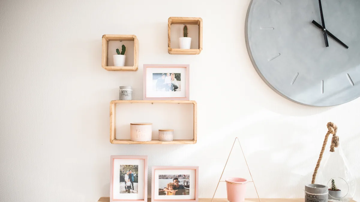 Living room wall with framed photos, open shelves and a large clock